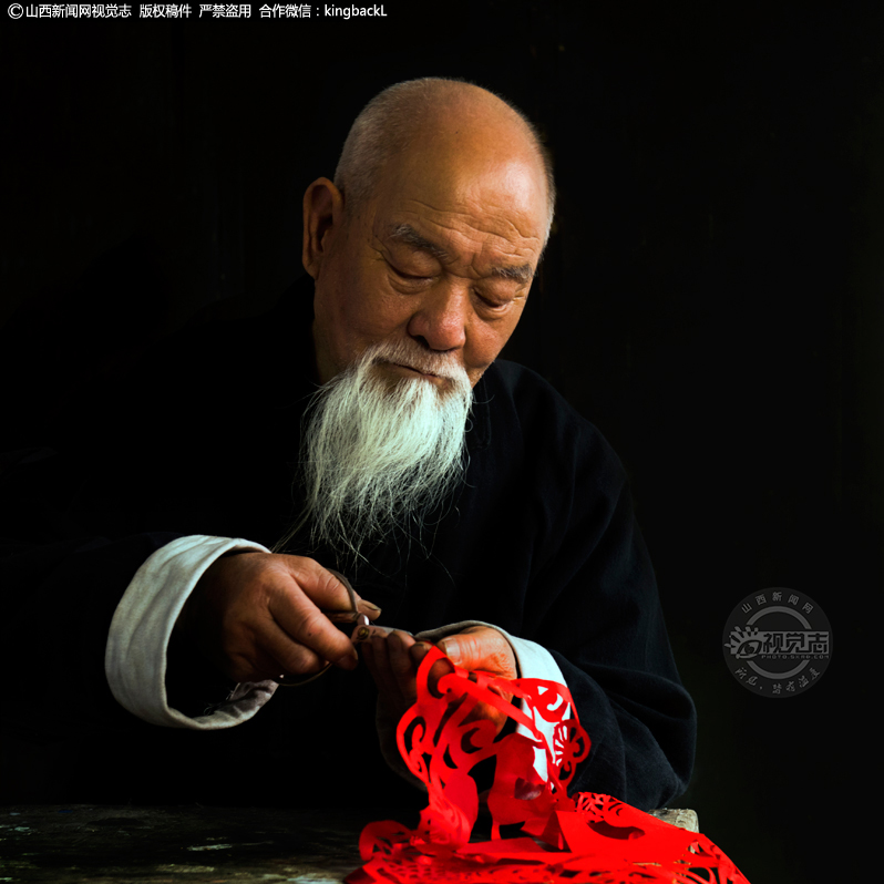      剪纸，又称剪花、窗花、刻纸，是中华民族源远流长的民间工艺。王森玉，今年77岁，山西省寿阳县宗艾镇宗艾村人，王森玉老人的民间剪纸来源于生活之中，艺术构思巧妙，精致典雅，令人喜爱。作品有生肖、脸谱、福寿、校园文化系列、社会主义核心价值观、抗日战争故事等多个系列，颇具山西民俗风情特色，题材新颖独特，常用夸张的剪纸语言表达当地的民俗民风，作品中蕴涵着奔放、热情的情调和韵味。王森玉把满腔热心都投入群众文化事业中，在建设农民文化阵地，活跃农民文化生活，培养农村文化骨干等方面做出了突出贡献，先后受到省文化厅、市县文化部门表彰奖励。（■山西新闻网特约摄影师：聂行明）