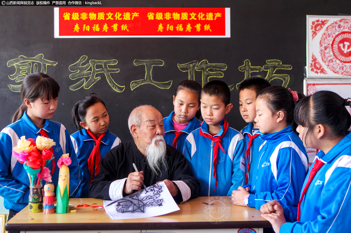      王森玉老人在宗艾镇小学给学生们传授剪纸艺术。