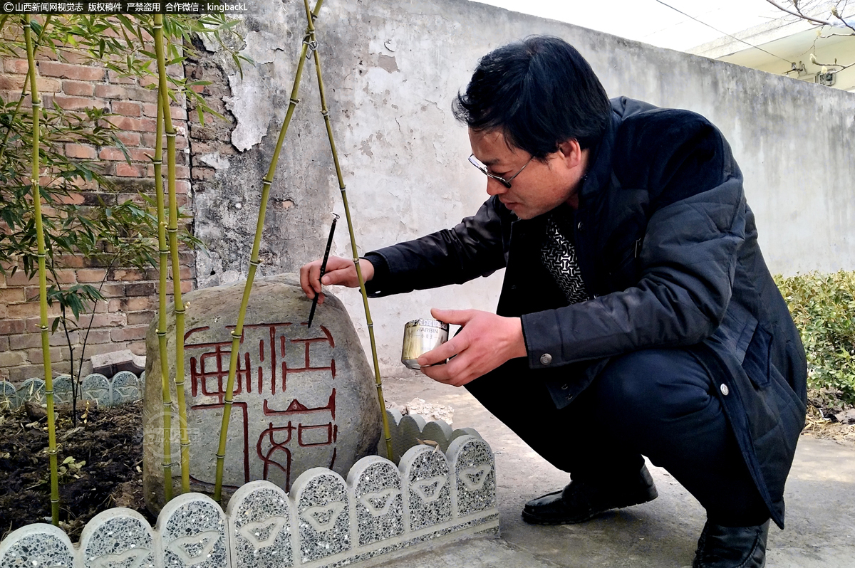      诊所大门西边有一块范忠红种植的“小竹林”，闲暇之余的他在给一块刚刻好的“江山如画”的石头补漆、修形。