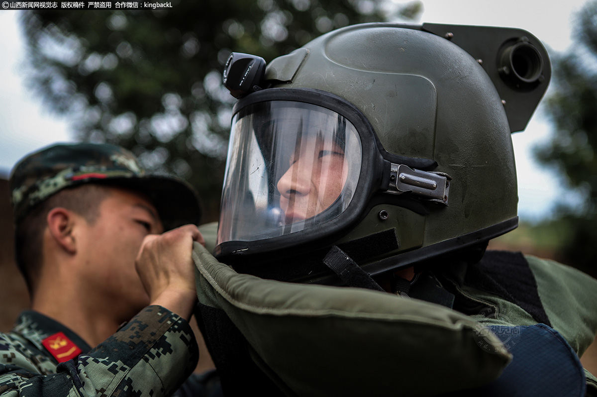      高温酷暑下，排爆手在队员的协助下穿上70斤重的排爆服。