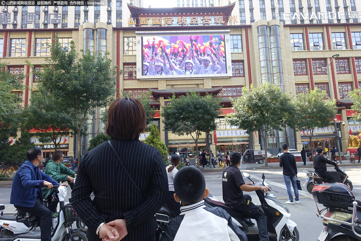      10月1日，太原小店区许东路附近古玩城前，路过的市民驻足观看阅兵直播。（山西新闻网特约摄影师：郝仁喜）