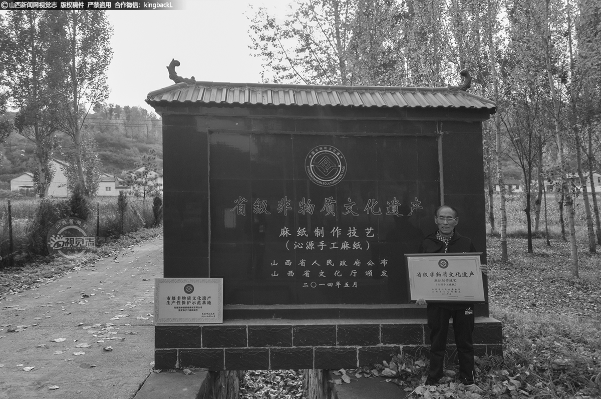      郑变和，今年64岁，是第四代手工麻纸的传承人，根据家族传承谱记载，郑家手工麻纸，距今已远超百年历史。他年轻时就和父亲开始学做麻纸，那时及之前麻纸是农村百姓常用的东西，糊窗子、贴炕围、打隔层、药店包药、食品店裹吃的、书写各种契约合同、毛笔书写用纸等，家家户户都离不开它。后来随着农村房屋建设材料结构以及生活、文化习惯的改变，麻纸使用量就越来越少了，特别是80年代后，周边的麻纸制作作坊纷纷倒闭，基本都金盆洗手了。村口这块省级非物资文化遗产公示标志是2014年由政府所建。（■山西新闻网特约摄影师：南志平 胡波）