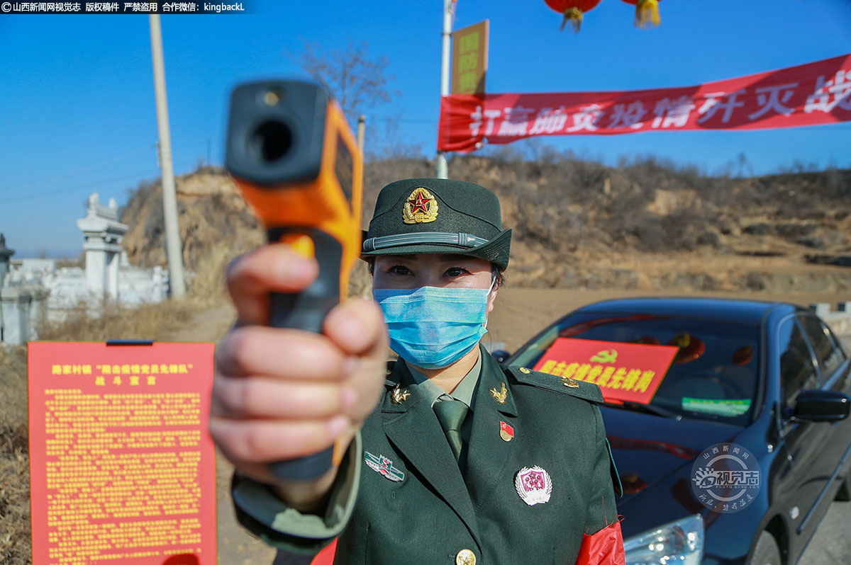      女子民兵班队员在村口为过路人员测量体温。在疫情牵动人心的时刻，民兵班的队员们为全力打赢疫情防控阻击战，舍小家顾大家。