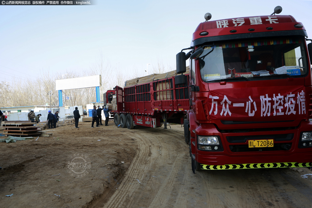      一辆卡车载有建筑、装饰材料驶入工地，车前方悬挂着“万众一心，防控疫情”条幅。据了解，临汾市第三人民医院异地新建项目门诊医技综合楼B栋共6层，设计病房54间，观察室5间，ICU病区一个，设置病床120张，所有病房均为“负压病房”，能有效满足隔离、收治确诊患者需求。