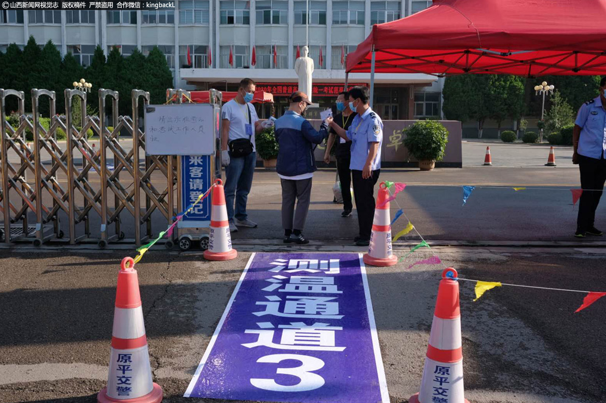      山西省原平市范亭中学考场外，工作人员正给考生测量体温。（山西新闻网特约摄影师：聂建伟）