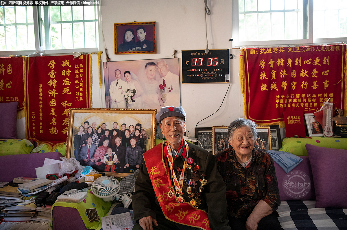     刘老的爱人叫葛新，比他小两岁。他们是1943年白求恩国际卫生学校的同学，于1948年结婚。在纪念中国人民抗日战争胜利75周年这个特殊的日子，他们在家里留下了这张合影。身后是他们80岁时的婚纱照，以及2007年的全家福。