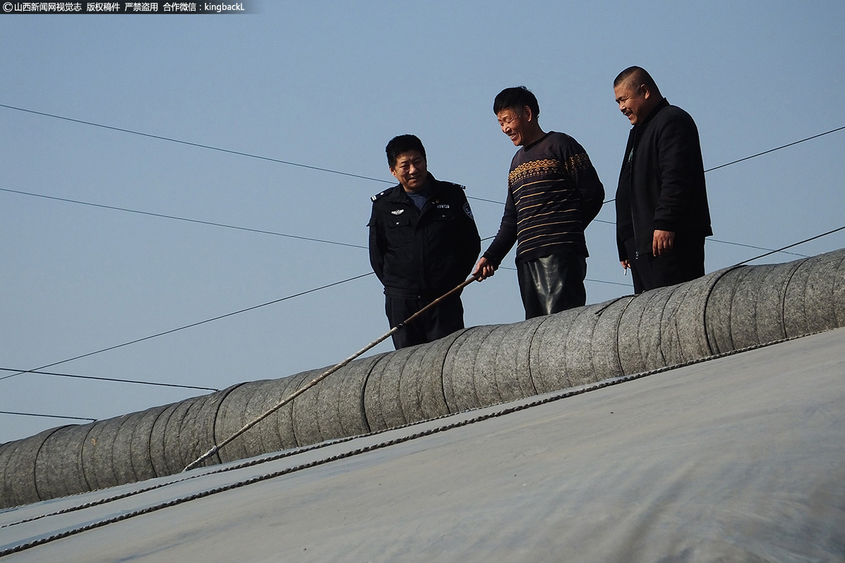      56岁的建档立卡贫困户闫海潮（中）同驻村第一书记交警张卫东（左）和村干部闫益林在忙活着给蔬菜大棚放气。张卫东与老百姓天天在一起，懂他人之辛苦，了解他人之所需，才能更好的为村里的百姓服务。