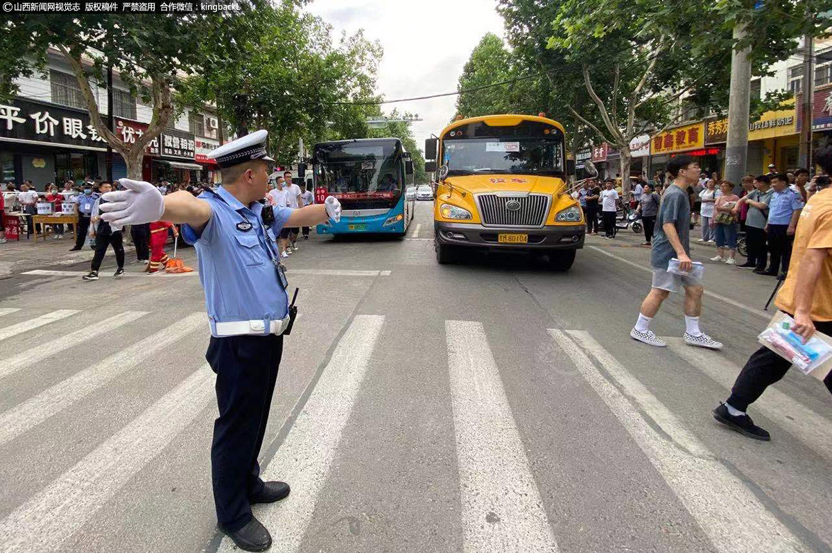      6月7日，运城市盐湖交警大队民警在盐化中学考场门口指挥交通。（山西新闻网特约摄影师：党永立）