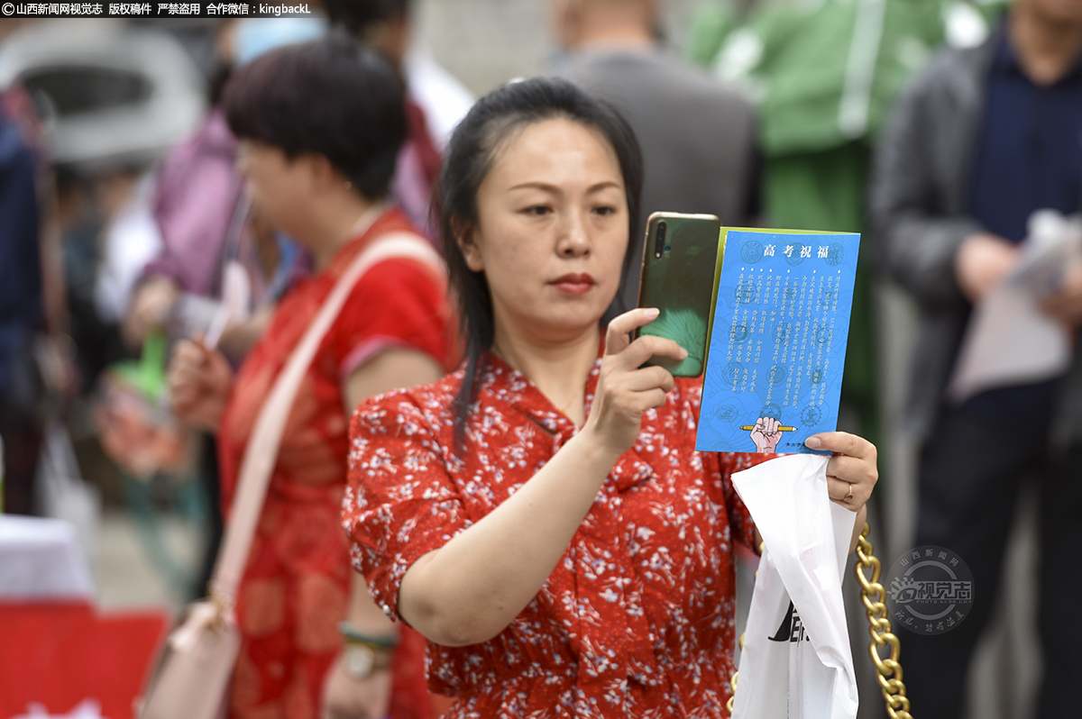      6月7日，太原市第二外国语学校考点，一名家长拍摄商家赠送的考生祝福。（山西新闻网记者：苏航）