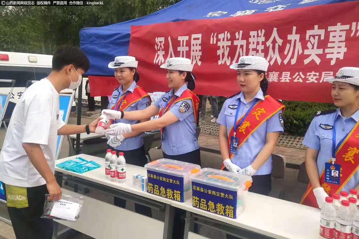      6月7日，定襄中学考场外，民警为考生贴心送上水。（山西新闻网特约摄影师：班建勇）