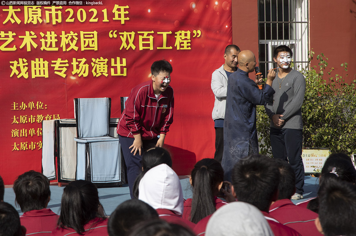      为了能使学生对戏曲产生兴趣，演员们经常互动，把学生请到舞台上，给他们化妆。图为小男生被画了丑角脸谱，台上台下的孩子们笑的前仰后合。