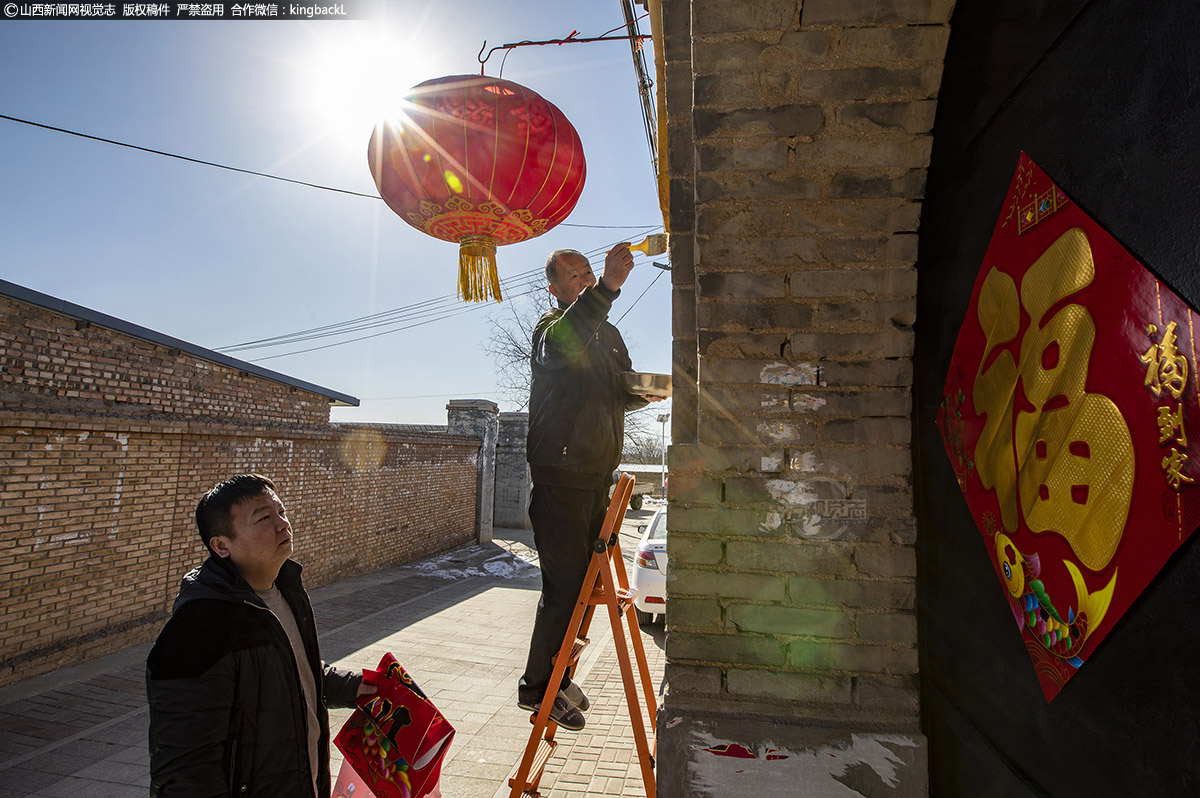      老韩父子俩非常认真的贴大门上的对联，儿子小韩常年在县城居住，今天带全家回来过年，可以与父亲一起贴对联，也是难得的一场相聚。