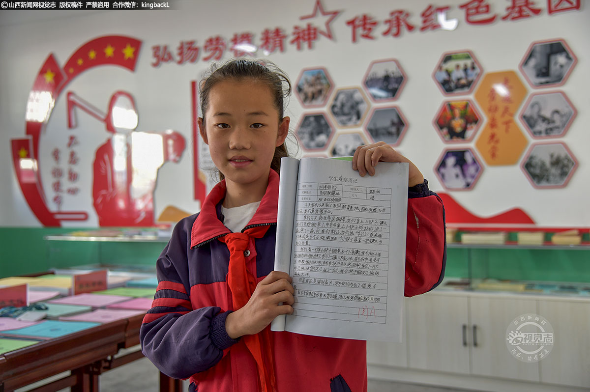      一名小学生展示自己的在劳动教育课中，关于对西红柿除草的观察周记。