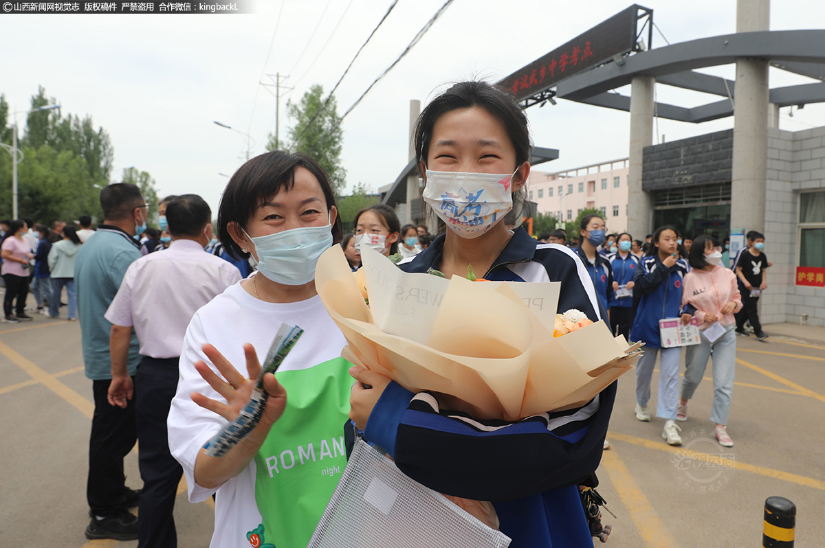      6月7日，高考首场考试结束后，在山西省长治市武乡中学考点，一位学生家长为孩子送上献花，孩子口罩上印有“高考加油”字样。（山西新闻网特约摄影师：李勇）