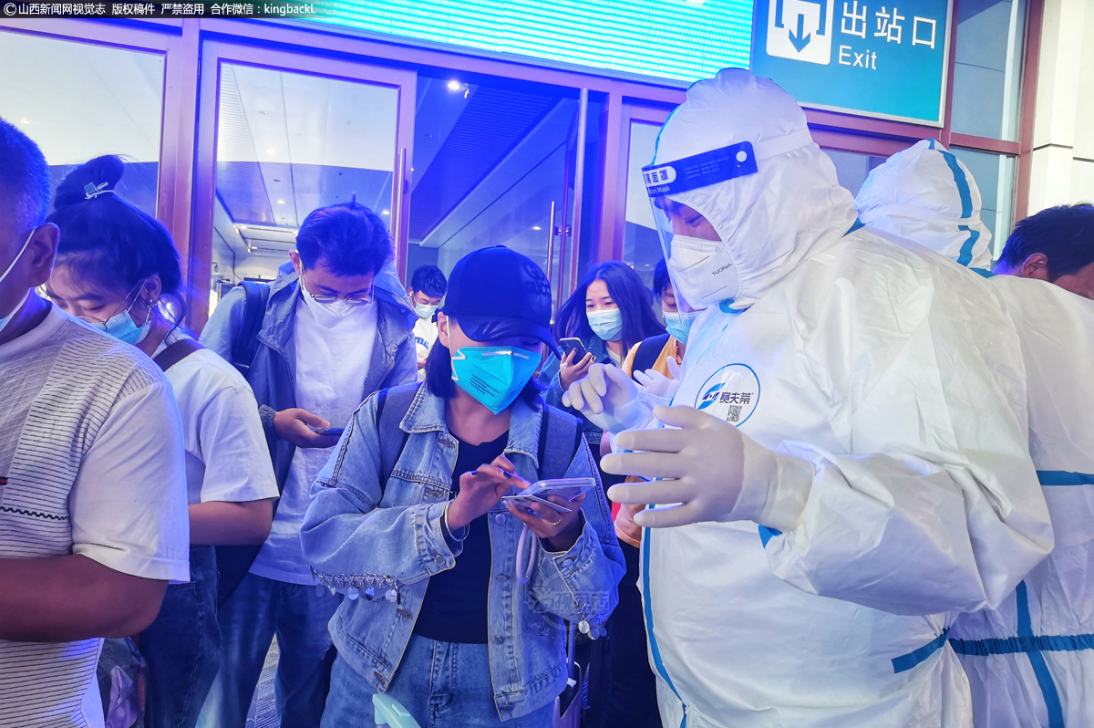      车站防疫人员根据行程码分流省外乘客和高风险地区来长的乘客，图为防疫人员正在认真检查每一个旅客的行程码。