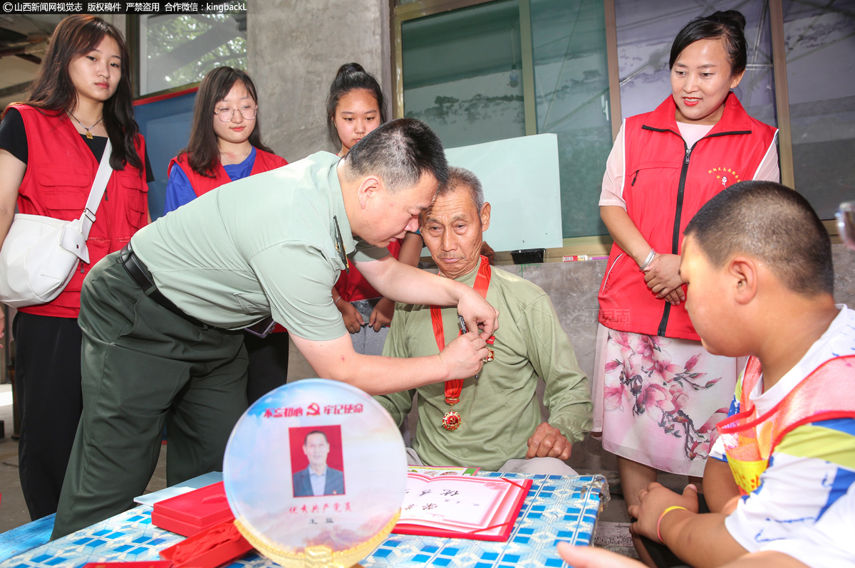      抗战老兵王益为志愿者们讲述当年战斗的经历，仿佛又一次回到了战场上，贾峰耀同志为王益整理军容，佩戴军功章。