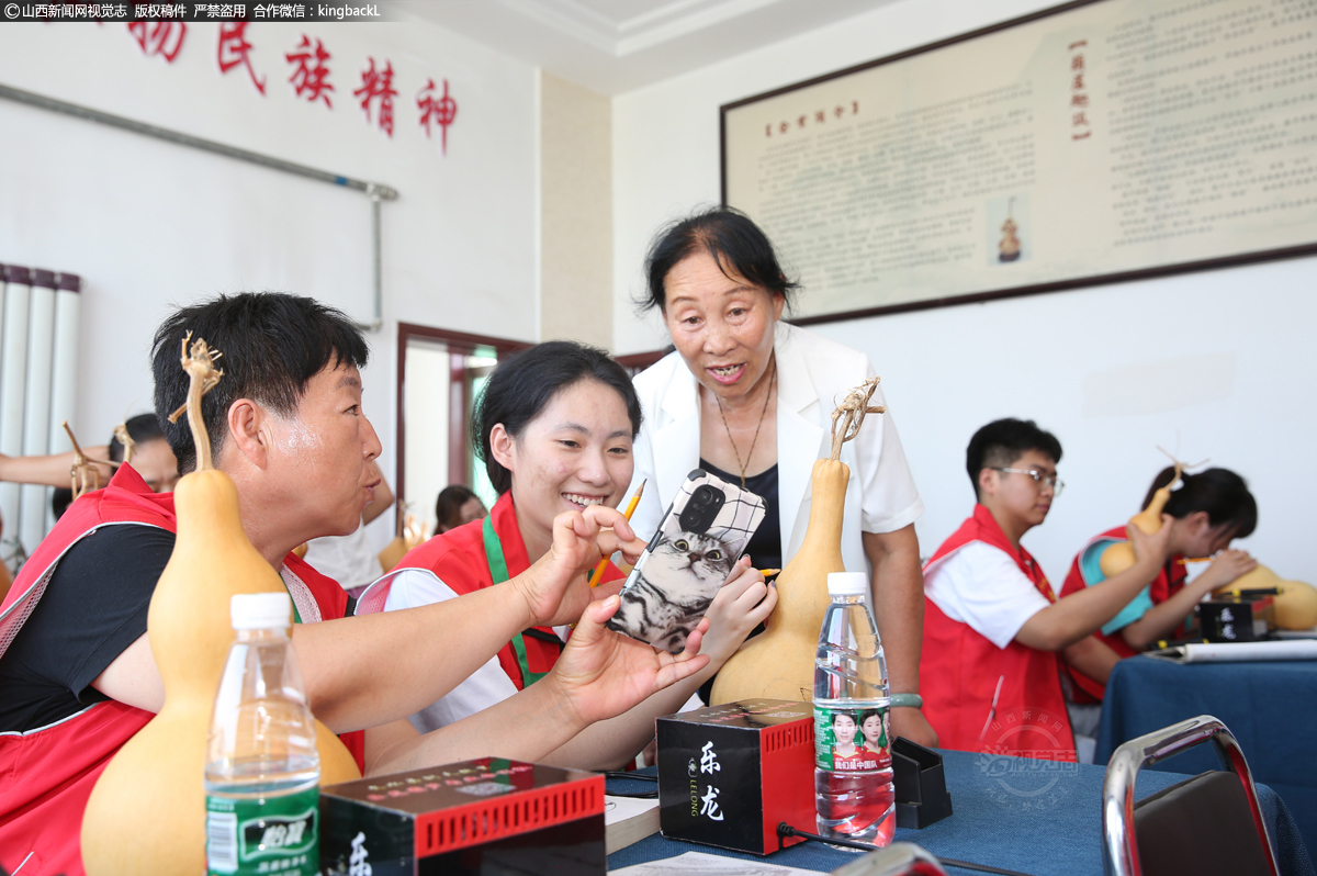      薛改莲正极具耐心地为志愿者讲解烙画工艺操作方法，并为志愿者解决制作过程中的各种疑惑。