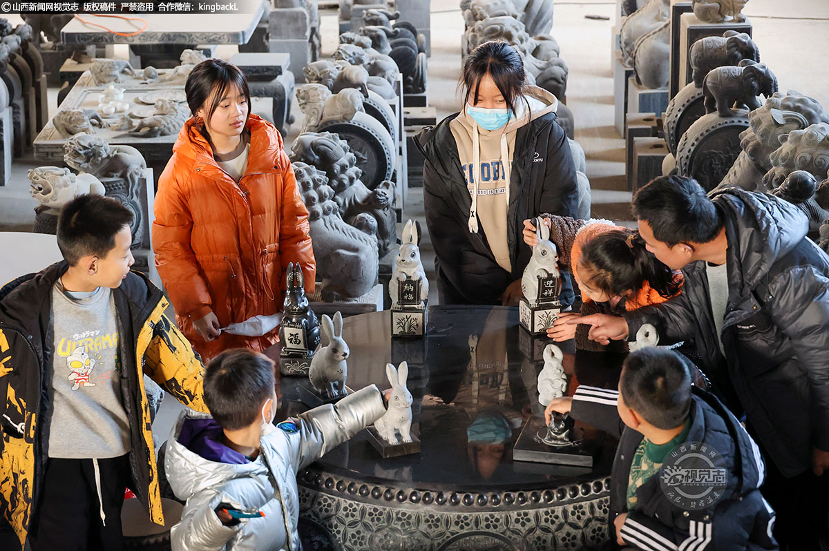      图为非遗绛州石雕市级传承人家金辉（右）为小朋友介绍兔年系列生肖绛州石雕。扬眉“兔”气、“兔”飞猛进、宏“兔”大展、玉“兔”呈祥、前“兔”似锦等，每个“兔子”都有它的专属名字。
