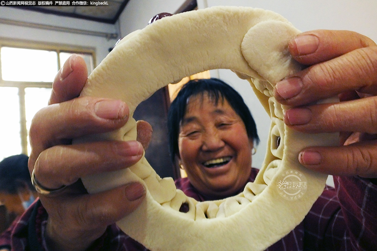      在新绛县泽掌镇泽掌村馍铺，捏花馍能手刘玉娥在展示捏制的节节高花馍底座。在这里，一个个浑圆的面团经过一双双巧手，就变成了生动的飞禽走兽、花鸟鱼虫......