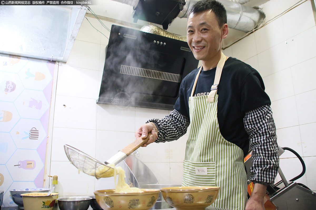      段志勇正在给客人捞面，中午时分饭店里来了两个闻名而来的小区居民。