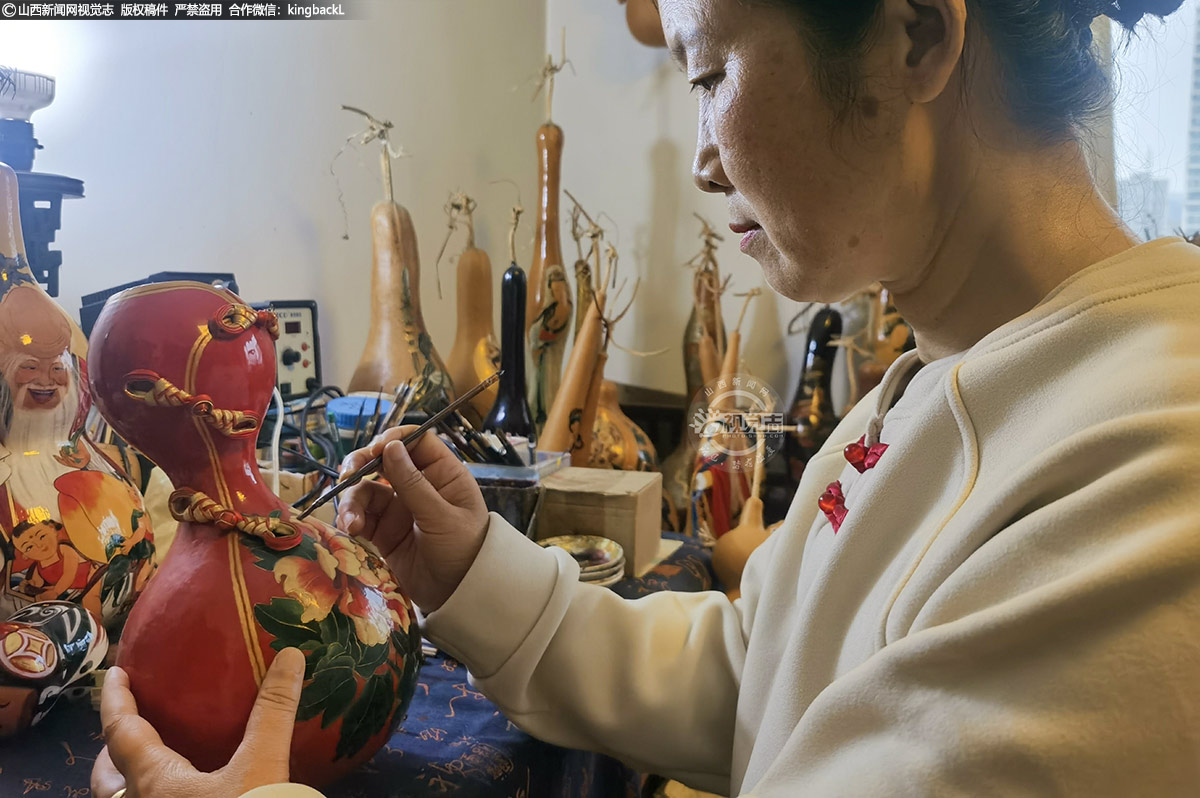      而宋老师则在一旁，用烙笔在葫芦上绘制年画人物，笔触起伏间，线条流畅飘逸，伴随着缕缕青烟与淡淡焦香，一个个栩栩如生、灵动逼真的人物形象跃然于葫芦之上。墙上高悬的“葫芦张”牌匾，无声地诉说着这个家庭的葫芦情缘与艺术追求。