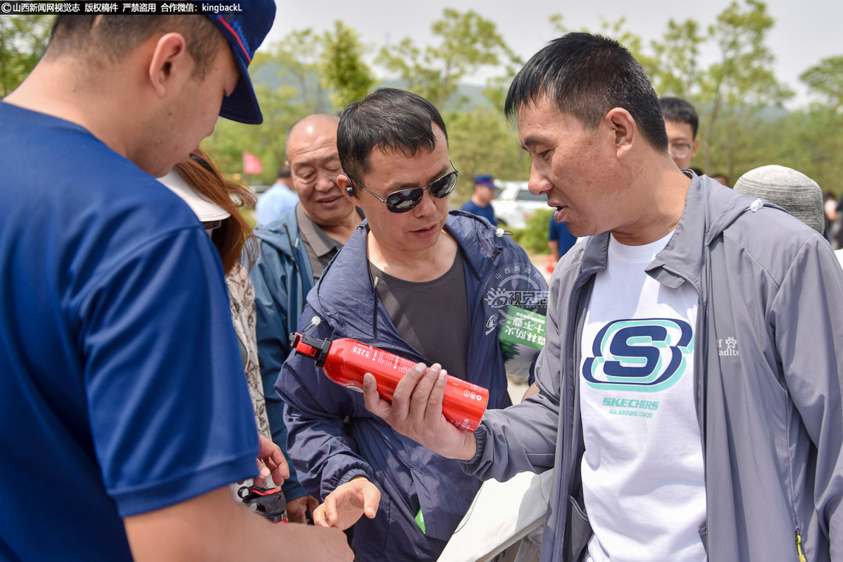      游客正在了解便携式灭火器的使用方法。工作人员详细介绍灭火器材的特点和使用场景，提升群众应急自救能力。