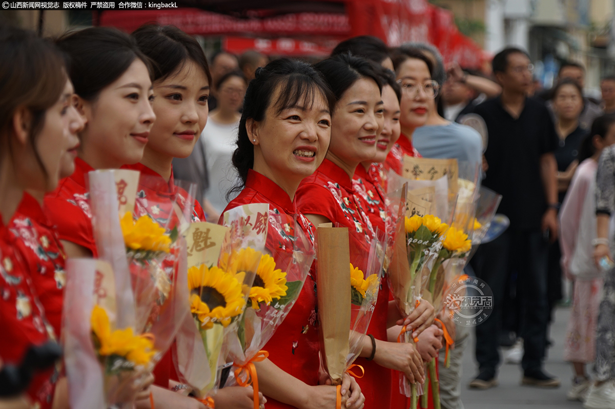      6月7日，在山西运城市理想学校高考考点，志愿者们身着旗袍，手拿鲜花，为参加高考的学子们送上祝福。山西新闻网特约摄影师：马双龙