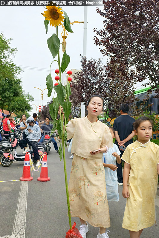      6月7日，在临猗中学考点，考生有序进入考场。有的家长穿着旗袍、手拿向日葵，寓意旗开得胜、一举夺魁。山西新闻网特约摄影师：党永立