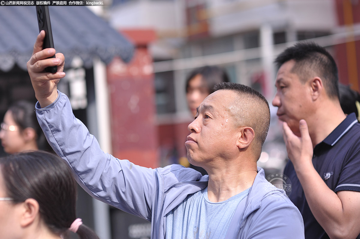      6月7日，山西太原，一位父亲用手机记录孩子入场瞬间，大汗淋漓。