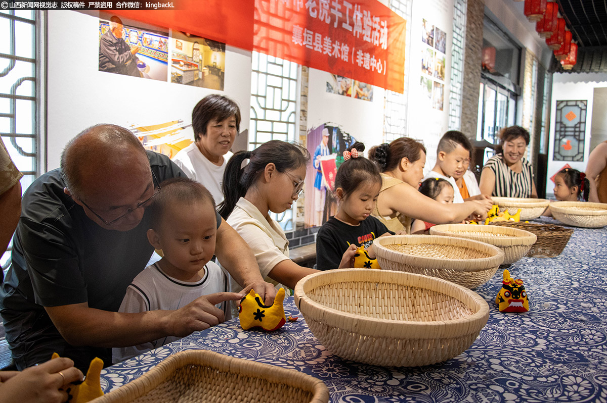      在襄垣县美术馆（非遗中心）开展的“暑期趣享非遗 亲子共制布老虎”活动中，孩子们与家长围坐一起，为“襄虒虎”坯体粘贴装饰，憨态可掬的布老虎在指尖渐显灵动。除亲手制作外，孩子们还在讲解员带领下，于织布机前感受经纬交织的智慧，在炕围画前聆听民俗故事，一件件馆藏老物件此刻成为穿越时光的生动教材。