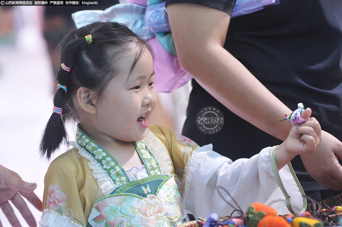      8月21日，身着汉服的小女孩看着喜欢的饰品欣喜不已。