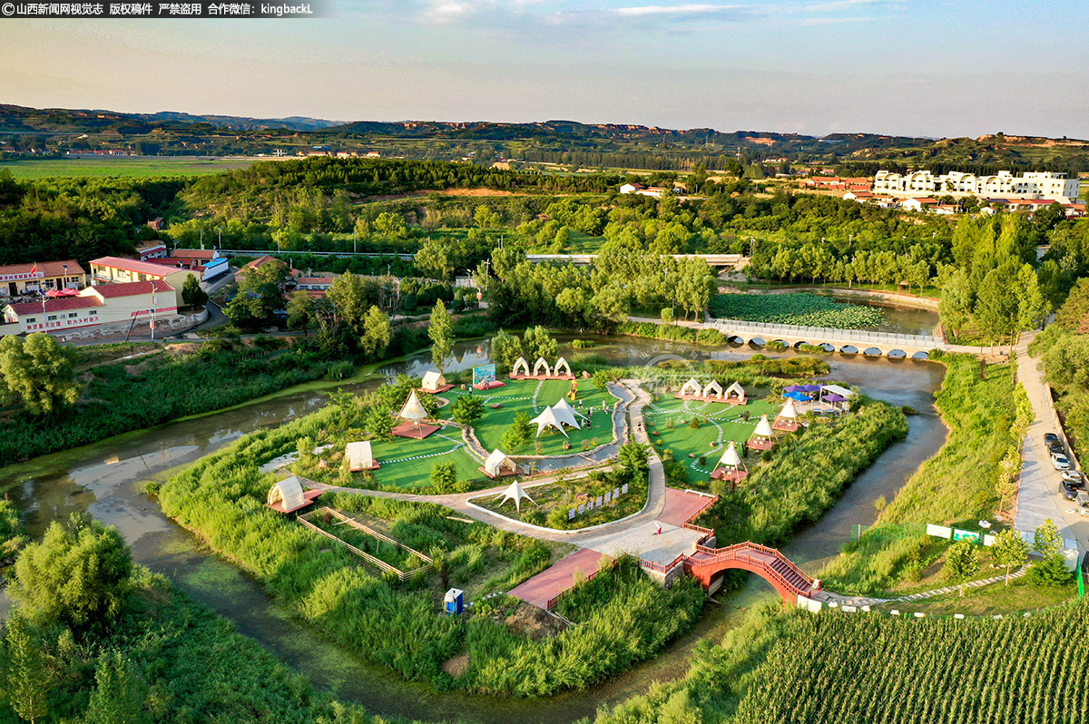      盛夏的环宝峰湖风景区风光如画、摇曳生凉。建华村的连片荷花与蓝白相间的“襄约・潮屿”建筑相映成趣。
